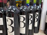 several bottles of red wine are lined up on a counter