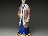une vieille figurine représentant un homme vêtu d'une robe et d'un chapeau