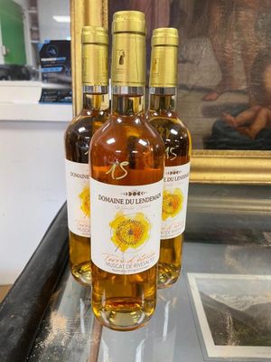 three bottles of wine sit on a glass table in front of a painting