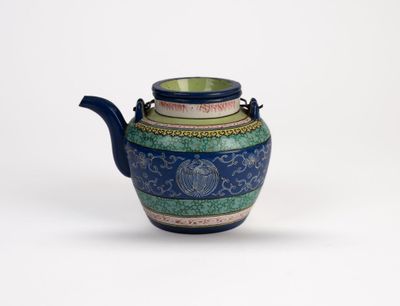a blue and green teapot sitting on a white surface