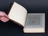 someone is holding an open book in their hand on a black background