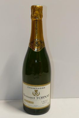 bottle of champagne on a white table with a white wall in the background