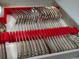 a box with a bunch of silver and red spoons in it