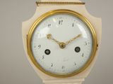 a white and gold clock that is on a table