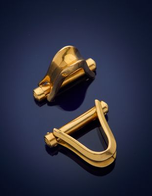 pair of gold plated brass hooks on a dark blue background