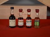 three bottles of liquor sit on a red cloth next to a wooden box