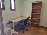 un bureau avec une chaise et une étagère dans le coin