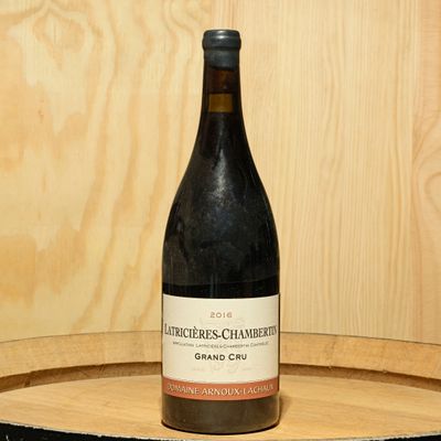 a bottle of wine sitting on top of a wooden barrel