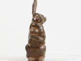 bronze sculpture of a rabbit sitting on its back on a white surface