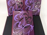 trois boîtes violettes et noires ornées de motifs violets sur un fond blanc