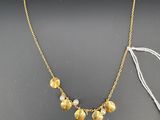 un collier doré et blanc composé de cinq petites perles montées sur une chaîne