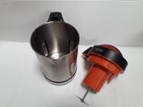 an orange and black blender next to a metal cup