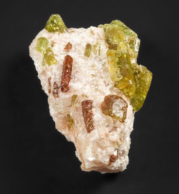 un morceau de roche présentant des cristaux verts et jaunes sur fond noir