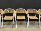 quatre chaises en osier sont alignées contre un mur noir