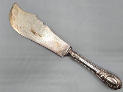 un vieux couteau d'argenterie à long manche posé sur une surface grise