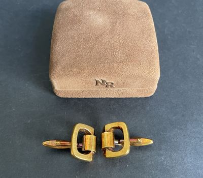 a pair of gold tone cufflinks and a brown sued case