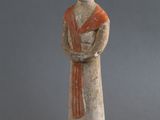 statue d'une femme tenant un bol de fruits à côté d'une banane