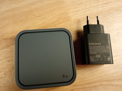 une petite boîte noire avec un chargeur posée sur une table en bois