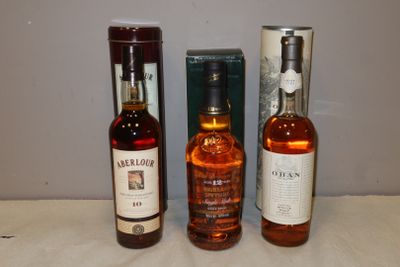 trois bouteilles d'alcool posées sur une table à côté d'une boîte