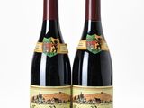 two bottles of red wine sitting next to each other on a white surface