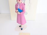 une figurine représentant une femme en robe rose tenant un gant bleu