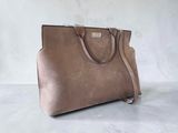 a brown handbag sitting on top of a white table