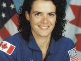 une photo d'une femme vêtue d'une combinaison spatiale bleue, prenant la pose