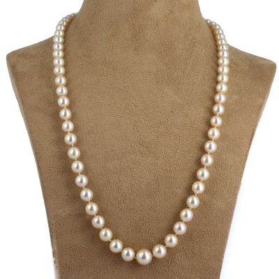 un collier de perles blanches sur un mannequin avec un fermoir en or