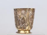 une coupe en or posée sur un socle en verre