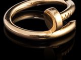 une image montrant un gros plan d'une bague en or posée sur une surface noire
