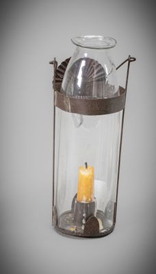 a glass lantern with a lit candle inside of it