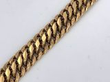 a close up of a gold chain bracelet on a white surface