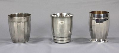 trois tasses en argent posées l'une à côté de l'autre sur une surface blanche