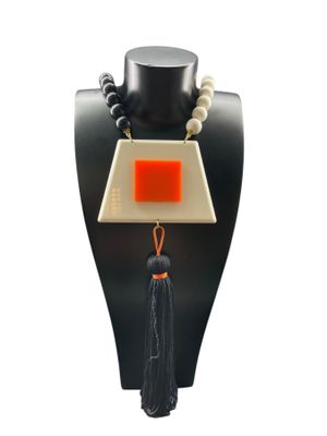 un gros plan d'un collier porté par un mannequin, orné d'un pompon
