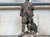 une statue représentant un homme tenant un chien sur une étagère en verre