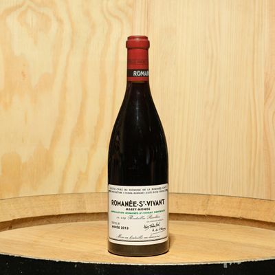 a bottle of wine sitting on top of a barrel