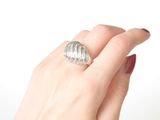 a woman ' s hand holding a silver ring on a white background