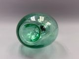 a green glass vase sitting on a white surface