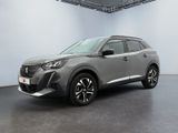 Une voiture grise est garée dans une grande pièce au sol noir.