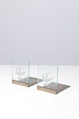 une paire de serre-livres en verre et en bois posés sur une surface blanche