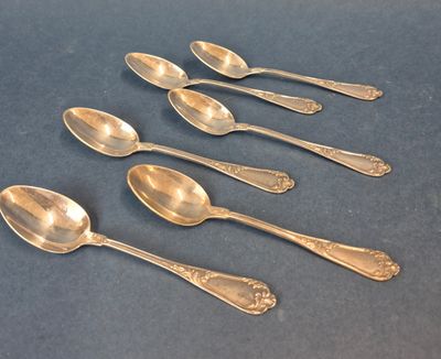six cuillères en argent sont alignées sur une table