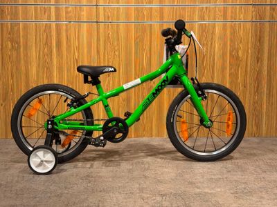 a green bike that is parked in front of a wooden wall