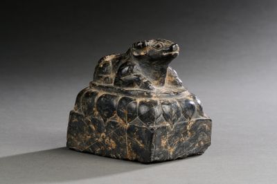 une image représentant une statue en pierre d'une grenouille assise sur un rocher
