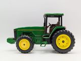 green toy tractor with yellow wheels on a white background