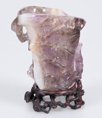 un vase violet posé sur un socle, sur une surface blanche