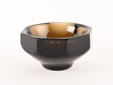 un bol noir et marron posé sur une surface blanche, avec un fond blanc