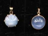 deux pendentifs en or sertis de pierres bleues et blanches, posés sur un fond de velours noir