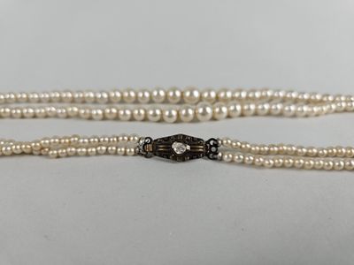 un gros plan sur un collier de perles blanches muni d'un fermoir noir