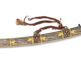 a gold and silver dagger with a red ribbon on it