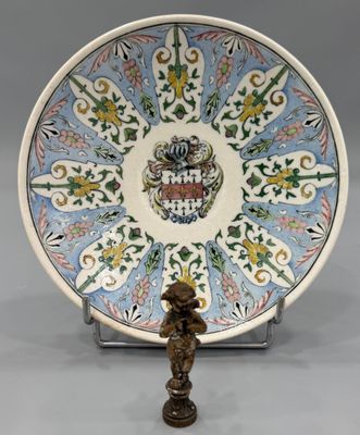une image représentant une assiette décorative sur laquelle se trouve une statuette posée sur un socle